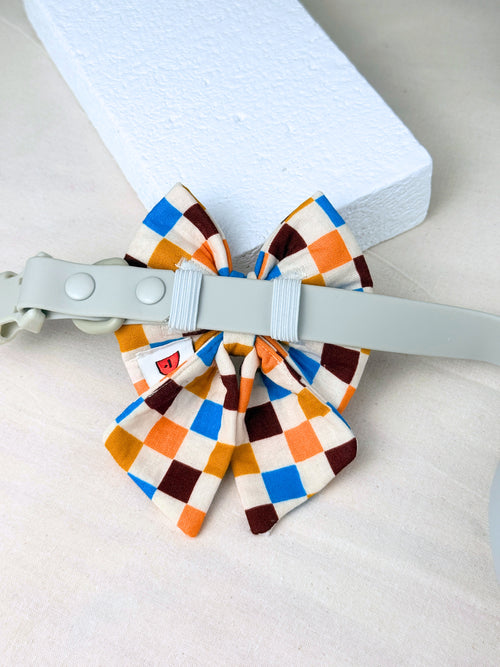 multicoloured checkered dog sailor bow on a dog collar showing the elastic straps