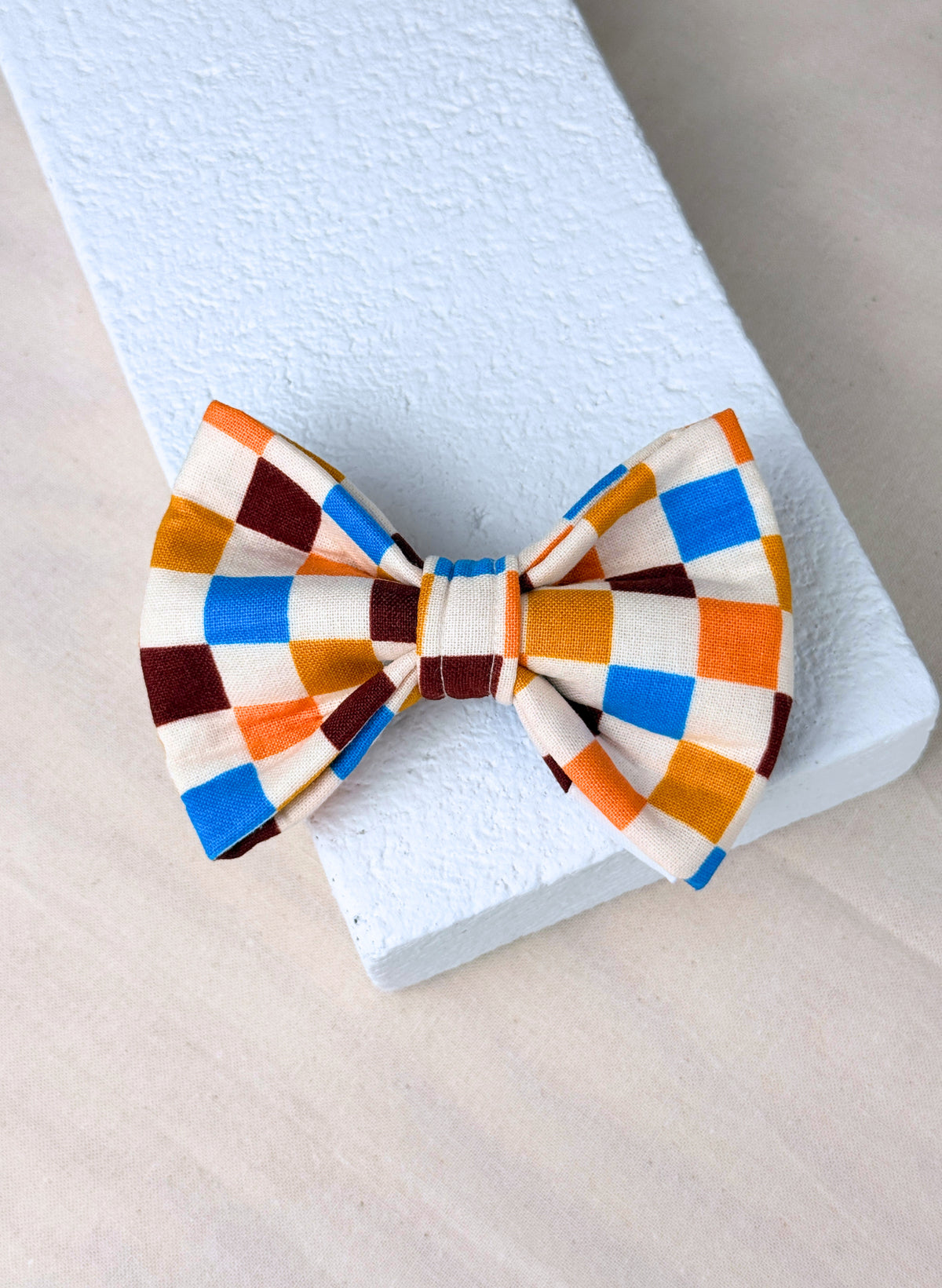 A multi coloured checkered dog bow tie